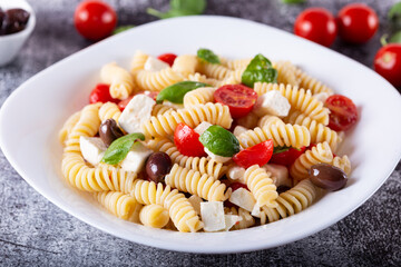 Greek-style pasta served with feta cheese, tomatoes and black olives. Typical dish of Greek and Mediterranean cuisine, suitable for a vegetarian diet.