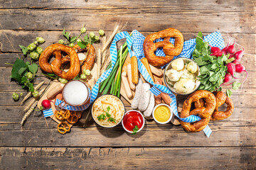 Oktoberfest holiday greeting card, menu, invitation background, Traditional Oktoberfest festival food, bavarian sausages, pretzels, potato, sauerkraut, beer mug on wooden background, copy space above