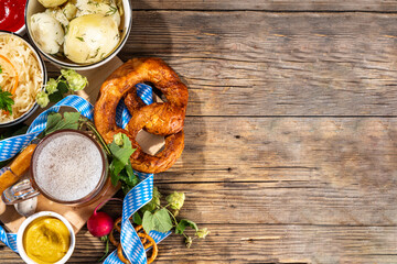 Oktoberfest holiday greeting card, menu, invitation background, Traditional Oktoberfest festival food, bavarian sausages, pretzels, potato, sauerkraut, beer mug on wooden background, copy space above