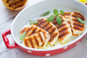 Red serving pan with slices of grilled haloumi cheese, close-up, selective focus