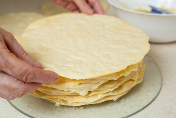 Making homemade Napoleon cake. After spreading the cream on the previous cake, put another one