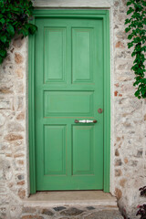 Fototapeta na wymiar Front Door of a Old Stone House. Green Street Door Close Up.