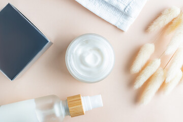 Face moisturizer cream, serum or beauty essential oil in frosted glass bottles on beige background. Flat lay, top view. Set for skin and body care beauty products.