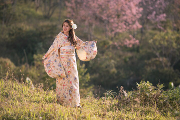 Young Asian woman wearing traditional Japanese kimono portrait in cherry blossom park.