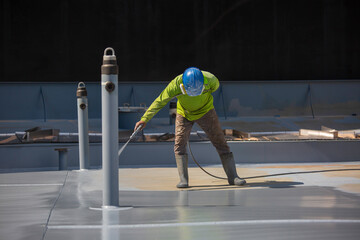 A male worker holding an industrial spray gun used for roof plate tank surface on steel industrial painting