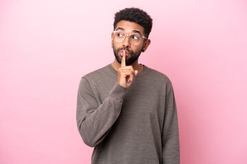 Young Brazilian man isolated on pink background showing a sign of silence gesture putting finger in mouth