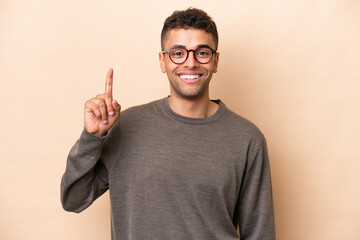 Young Brazilian man isolated on beige background pointing up a great idea