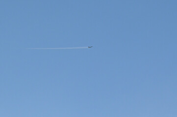 A jet fighter plane high in the sky above the ground.