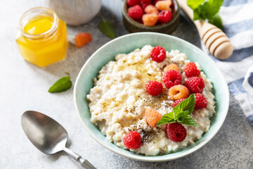 Oatmeal porridge in ceramic bowl decorated with fresh berries raspberries and chia seeds served with honey. Healthy diet breakfast.