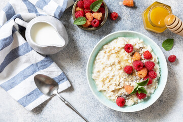 Oatmeal porridge in ceramic bowl decorated with fresh berries raspberries and chia seeds served with honey. Healthy diet breakfast. View from above.