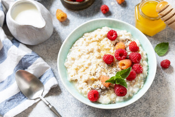 Healthy diet breakfast. Oatmeal porridge in ceramic bowl decorated with fresh berries raspberries and chia seeds served with honey.