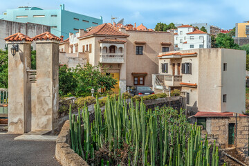 Fototapeta premium Residential buildings with a red tiled roof and a balcony in the town of La Laguna in Tenerife, Spain. Succulents grow near the fence of a Spanish villa in the Canary Islands