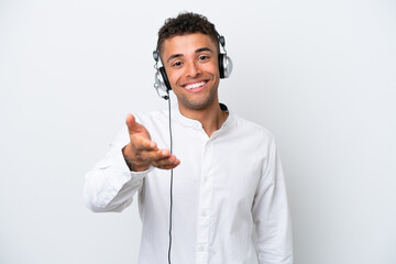 Telemarketer Brazilian man working with a headset isolated on white background shaking hands for...