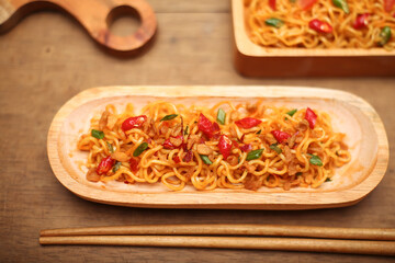 Instant noodles with chili pieces and spices in bowl on wooden table background. top view