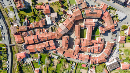 Top view of the orange roofs of houses standing in an interesting geometric shape of an Italian town in Liguria. Aerial photography - obrazy, fototapety, plakaty