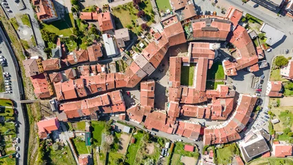 Poster Top view of the orange roofs of houses standing in an interesting geometric shape of an Italian town in Liguria. Aerial photography © annaleish