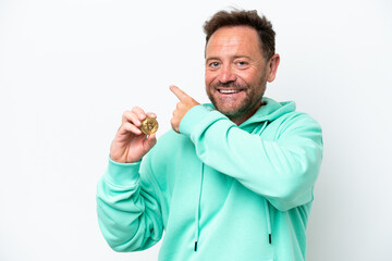 Fototapeta premium Middle age man holding a Bitcoin over isolated background pointing back