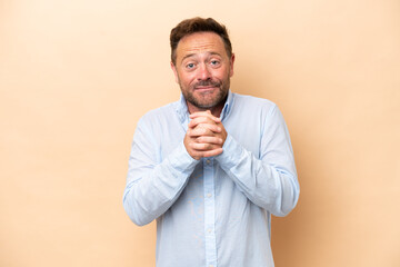 Middle age caucasian man isolated on beige background laughing