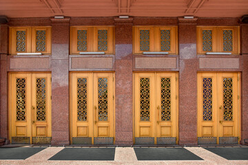 facade of old building is lined with marble entrance wooden doors and patterned glass windows...