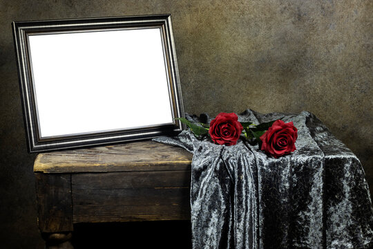 Empty wooden ornate picture frame photo with red roses flowers on wooden table with textile