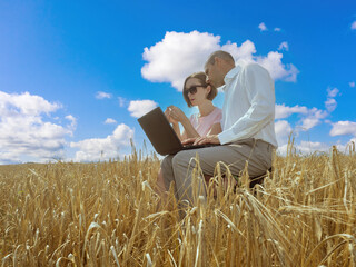 Naklejka na ściany i meble Man and woman in wheat field. Agricultural business managers. Heads agricultural company. Agro company managers with laptop. Modern farmers in wheat field. Concept software for agricultural business