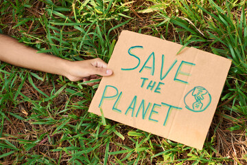 Recycled cardboard sign in the middle of the forest that says SAVE THE PLANET.