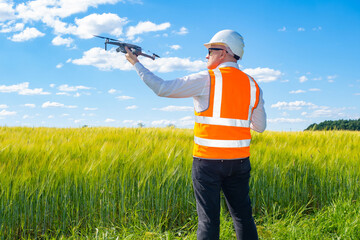 Surveyor engineer is holding drone. Surveyor with quadcopter on green field. Concept - builder uses...