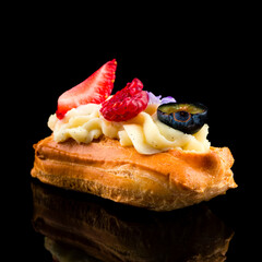 eclairs with glaze and strawberries on black