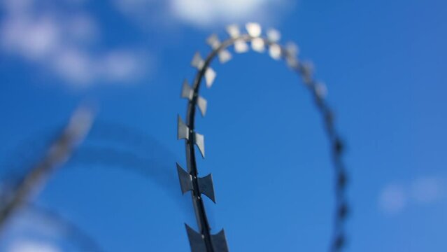 Free and peaceful sky with clouds on the background of barbed wire. Symbol of war and restrictions of freedom. Aggression and isolation, prison.
