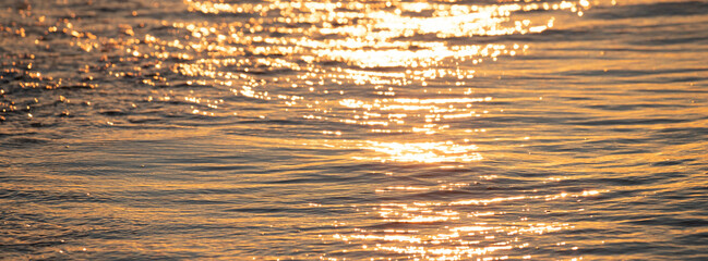 Surface water of sea or ocean at sunrise time with golden light tone.