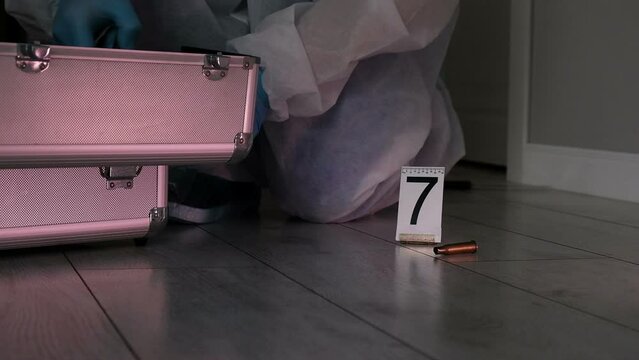 Forensic expert criminologist collects evidence at  crime scene, packaging of  fired cartridge case from  firearm, gloved hands close-up
