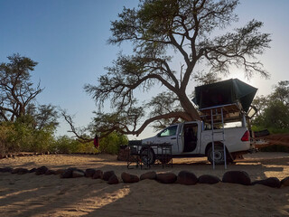 white 4x4 pickup with canopy and roof top tent on road trip © Jens