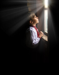 Small boy praying at the window