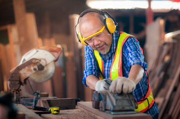 Asian elderly carpenter In workwear safety equipment uniform such as gloves,glasses, ear-muffs or...