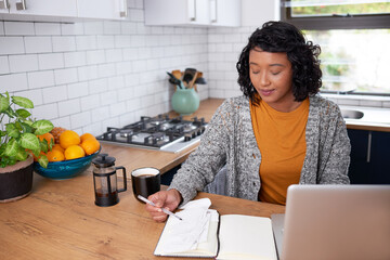 A young multi-ethnic woman reviews her household finances in the kitchen