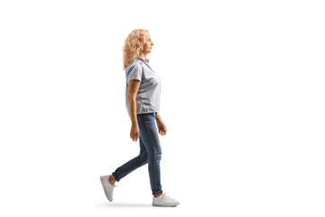 Full length profile shot of a casual woman in jeans walking - obrazy, fototapety, plakaty