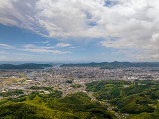 Fototapeta premium Aerial view of sprawling city at base of green hills