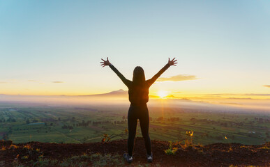 Fototapeta na wymiar strong confidence woman open arms under the sunrise at mountain