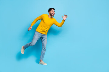 Full length photo of handsome excited guy dressed yellow pullover walking empty space isolated blue color background