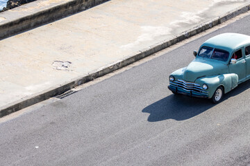 Old American vintage car driving in Malecon in La Havana, Cuba. Touristic and vintage colorful car.