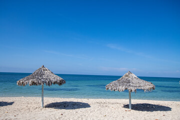 Paradise beach in Cuba with palm umbrella and clear blue water. 