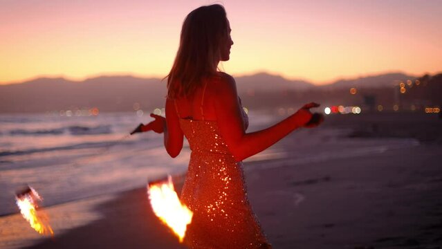Attractive woman fire dancer spinning flames at the beach. Slow Motion.