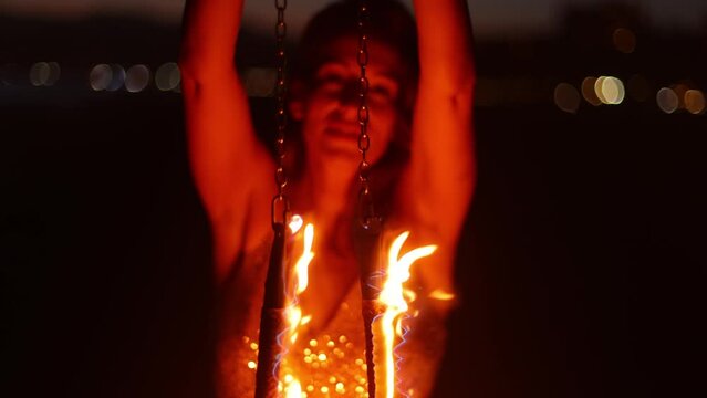 Attractive woman fire dancer spinning flames at the beach. Slow Motion.