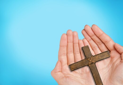 Human hand holding wooden cross crucifix. Catholicism, Christianity, Thanksgiving, Catholic and Christian faith concept.