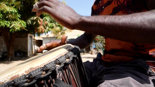 Slow motion footage of black hands playing djembe from the side with the focus on the closest hand