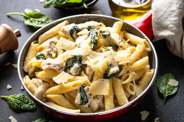 Pasta penne with chicken and spinach in creamy sauce in the skillet.