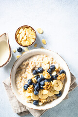 Oatmeal porrige with nuts and berries in craft bowl at white background. Top view.