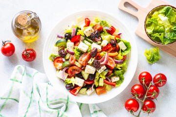 Greek salad. Vegetable salad with tomato, cucumber, feta cheese and olive oil. Top view on white stone table.