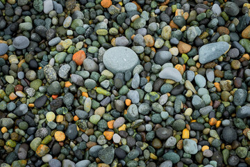 Pebble beach stones background, natural rounded gravel on the seashore nature background texture pattern. Wet pebble stones on the beach