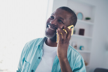 Portrait of cheerful aged man answer smart device call speak friend in modern house living room